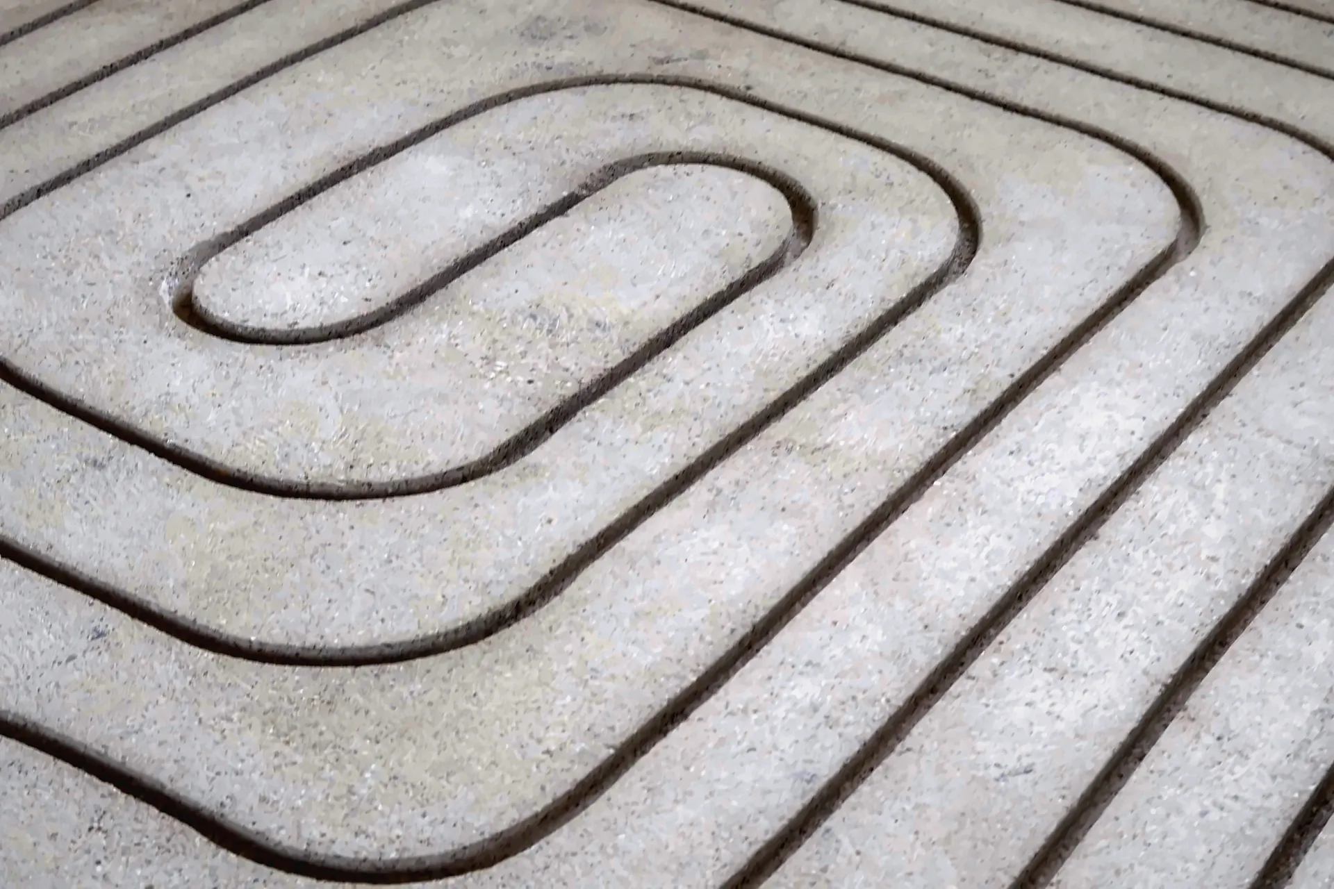 Gefräste Heizkanäle in abgerundeter Spiralform im hellen Estrich