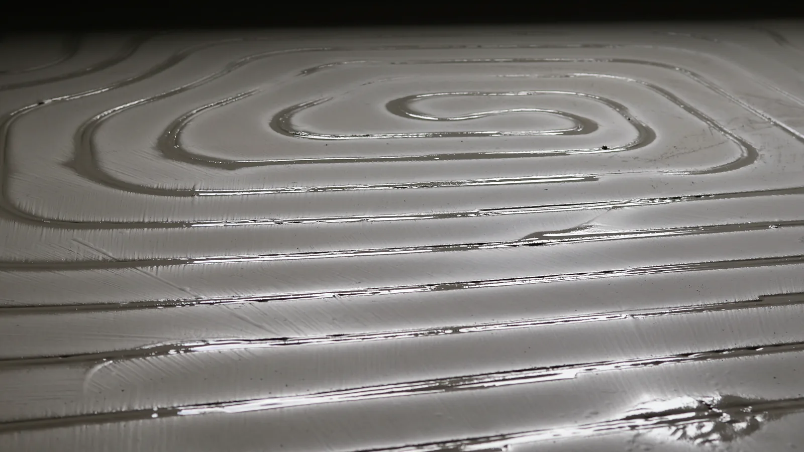 Frisch verfüllte Kanäle in Spiralform, die Masse glänzt noch nass im Streiflicht