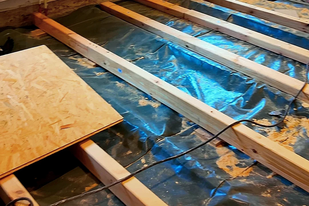 Holzbalken in Reihe auf dunkler Folie, links eine OSB-Platte, Standbild aus dem Reel „Neue Baustelle“ von XB