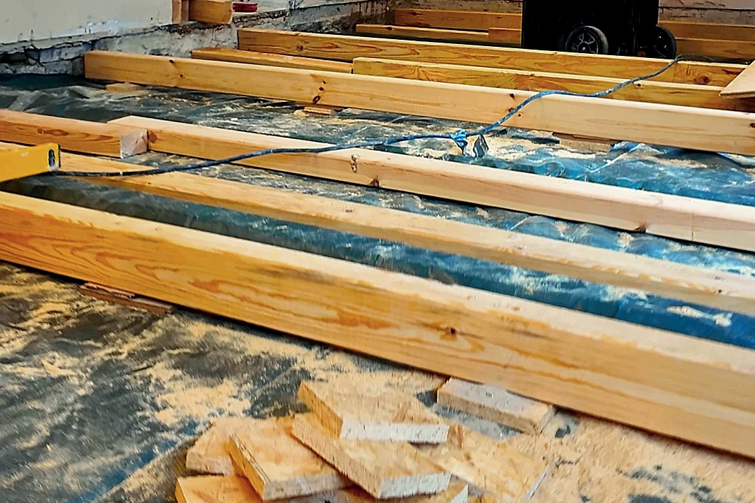 Lagerhölzer in Reihe auf dunkler Folie, davor Zuschnittreste von OSB-Platten