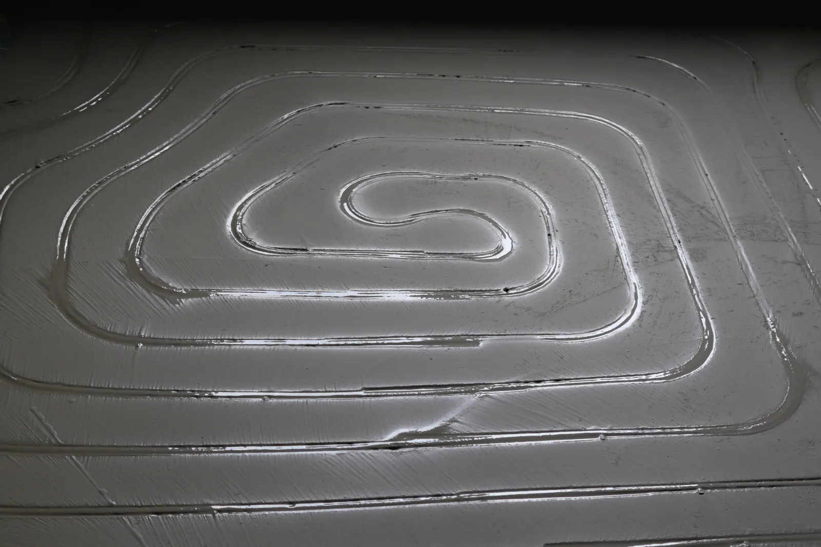 Verfüllte Kanäle in Spiralform, die Masse glänzt noch nass im Streiflicht